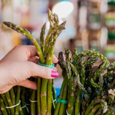 Frau greift nach grünen Spargelstangen